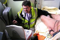 Dr Tomislav Petrovic examines a patient in an ambulance. Using a laptop-size...