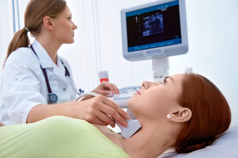 female doctor performing ultrasound thyroid examination in woman patient