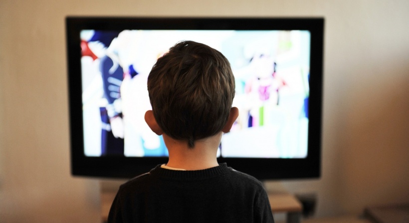 child sitting in front of tv screen