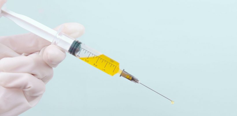 hand holding syringe with yellow liquid