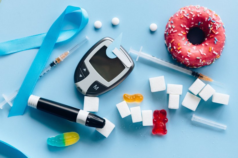 diabetes medical equipment and sugar, candy, donuts arranged on blue background