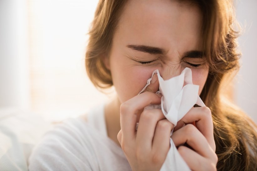 woman blowing her nose, sneezing from allergies