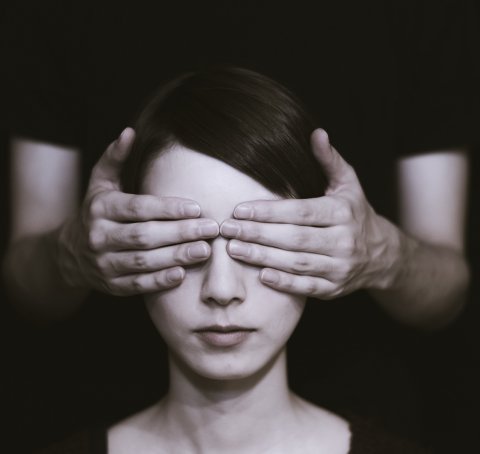woman having her eyes covered by hands of a person behind her