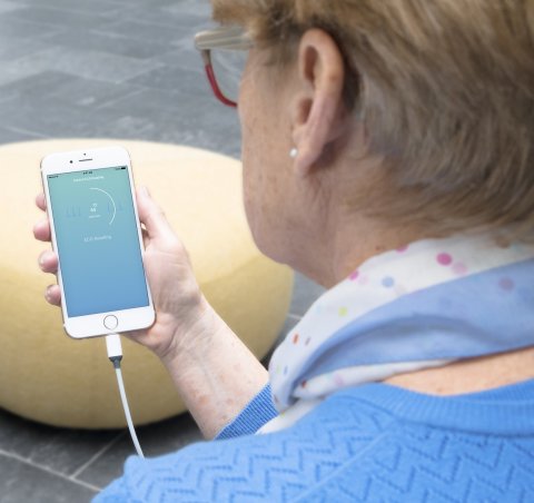 woman looking at a smartphone screen with ecg curve
