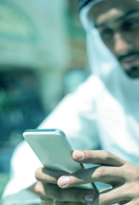 out of focus photo of sheikh in dubai looking at a smartphone