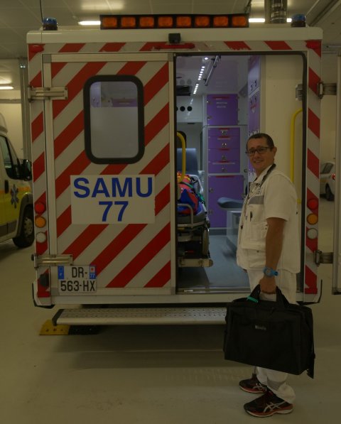 medic standing next to ambulance holding a black suitcase