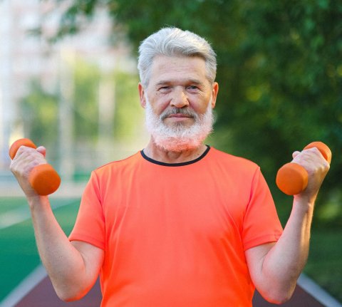 older man in orange shirt lifting small weights
