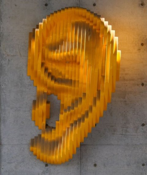 golden ear-shaped art installation on concrete wall