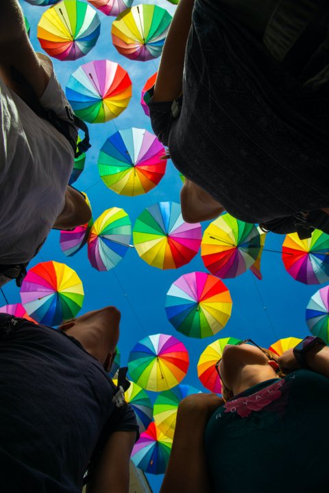 four people looking upward to colourful umbrellas