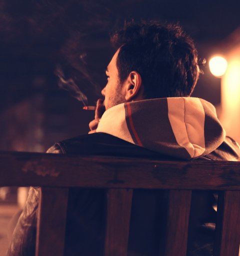 smoking man sitting on a bench